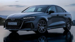 Front three-quarter view of the refreshed 2026 Audi RS3 luxury performance compact sedan speeding on a track, highlighting its aggressive new stance.