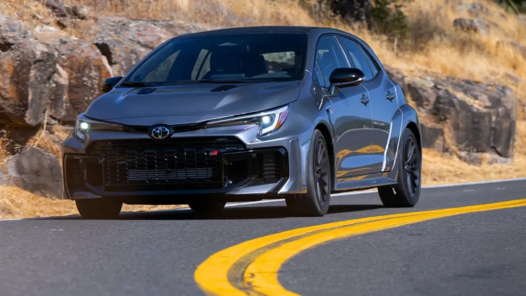 Heavy Metal 2026 Toyota GR Corolla driving on a winding road showing wide fender flares and front grille.